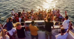 Grupo de pessoas a desfrutar de uma festa num barco durante o pôr do sol