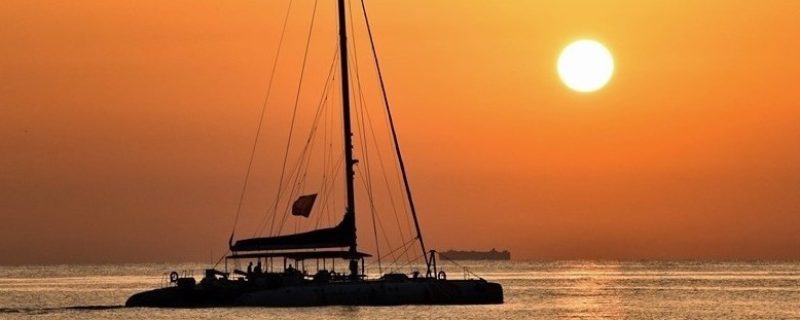 Catamaran enjoying a stunning orange sunset at sea in Valencia
