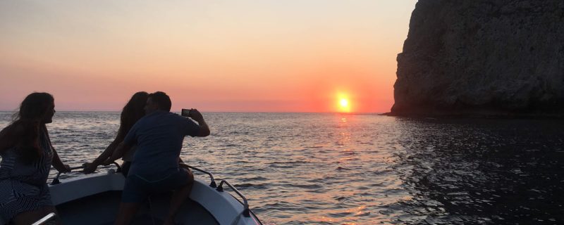 People on a boat watching the sunset in Sesimbra