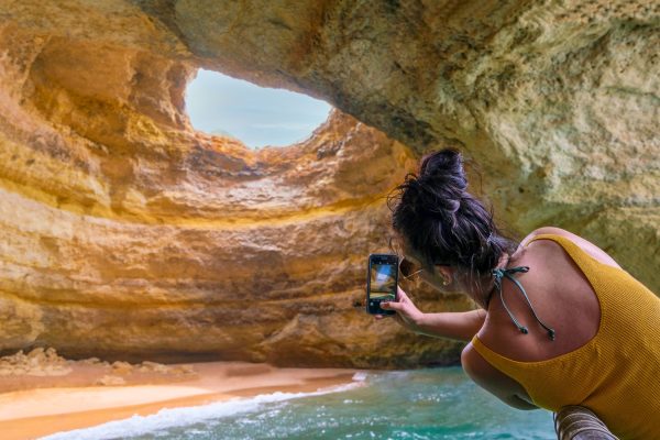 Girl taking picture of the Benagil Cave from a boat