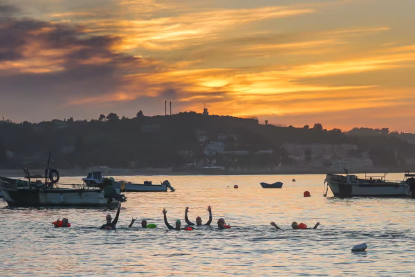 Group of swimmers in Cascais at sunset