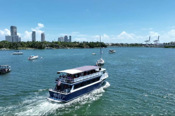 A large bi-level sightseeing boat cruising through the blue waters of Biscayne Bay.